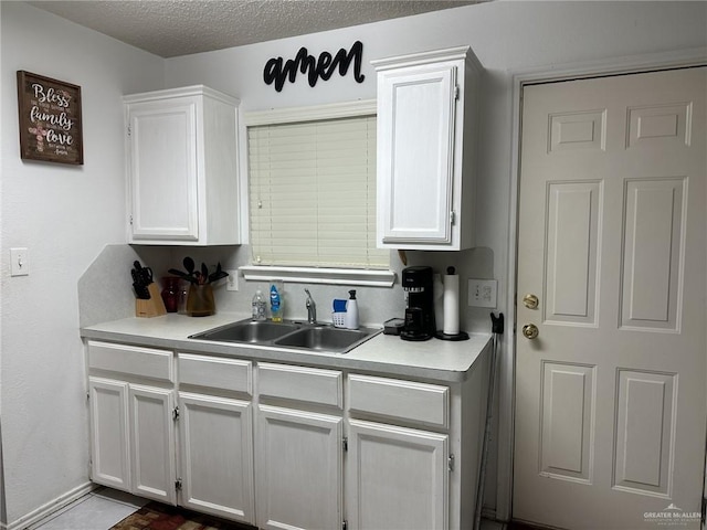 kitchen with white cabinets, a textured ceiling, and sink