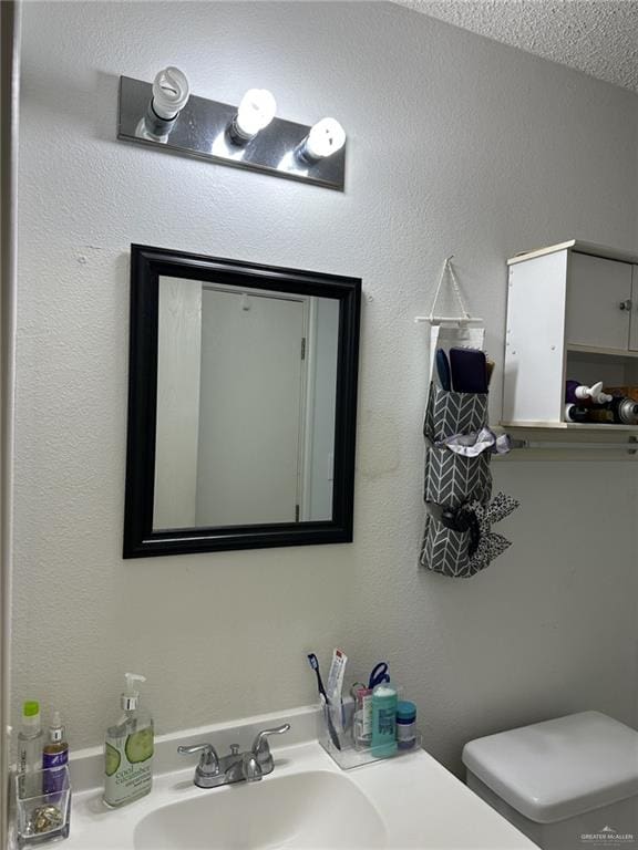 bathroom featuring vanity, toilet, and a textured ceiling