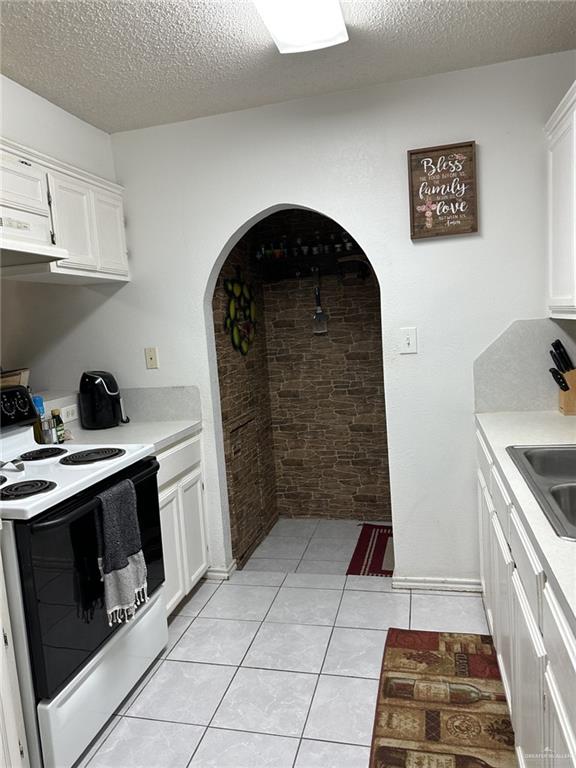2104 Fairmont Ave, Mcallen, TX 78504 - kitchen with white range with electric cooktop, light countertops, white cabinets, a textured ceiling, and light tile patterned floors