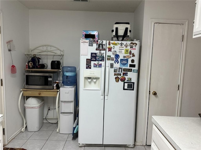 2104 Fairmont Ave, Mcallen, TX 78504 - kitchen featuring white fridge with ice dispenser, stainless steel microwave, white cabinets, light tile patterned floors, and light countertops