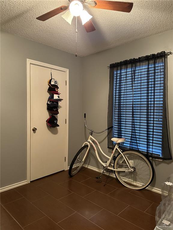 interior space featuring a textured ceiling, dark tile patterned floors, and ceiling fan