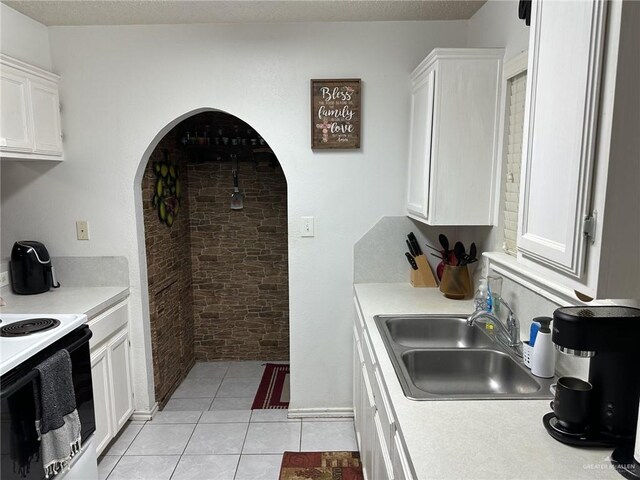 2104 Fairmont Ave, Mcallen, TX 78504 - kitchen featuring electric range oven, light countertops, white cabinets, light tile patterned floors, and arched walkways