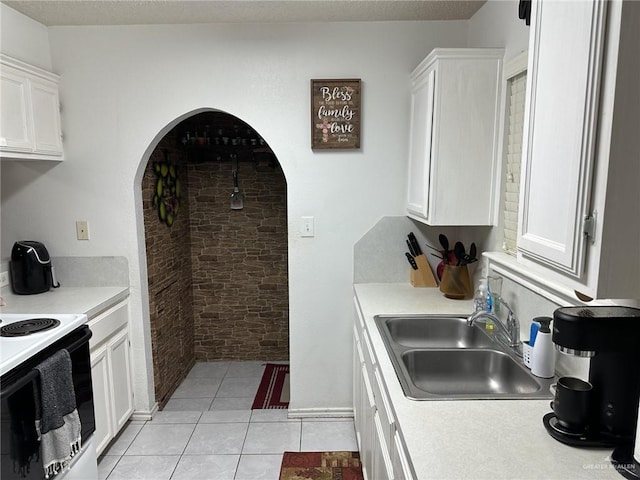 kitchen featuring white cabinets, light tile patterned flooring, and sink