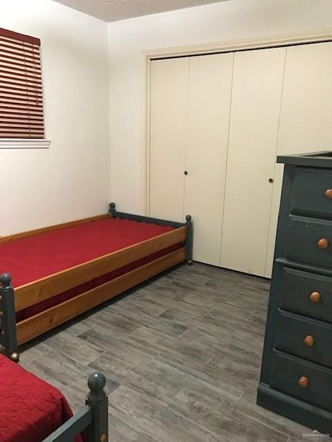 bedroom with dark hardwood / wood-style flooring, a textured ceiling, and a closet