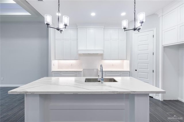 kitchen with white cabinets, sink, hanging light fixtures, and an island with sink