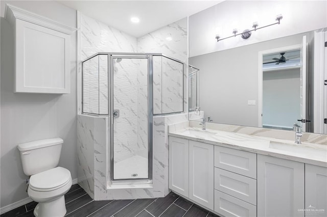 bathroom featuring vanity, toilet, ceiling fan, and a shower with shower door