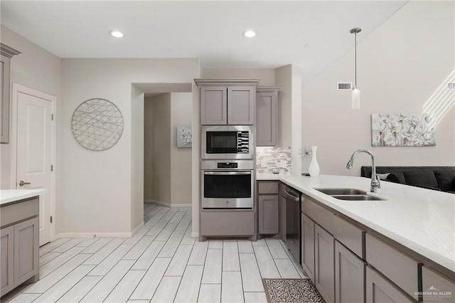 kitchen featuring gray cabinets, sink, pendant lighting, and appliances with stainless steel finishes