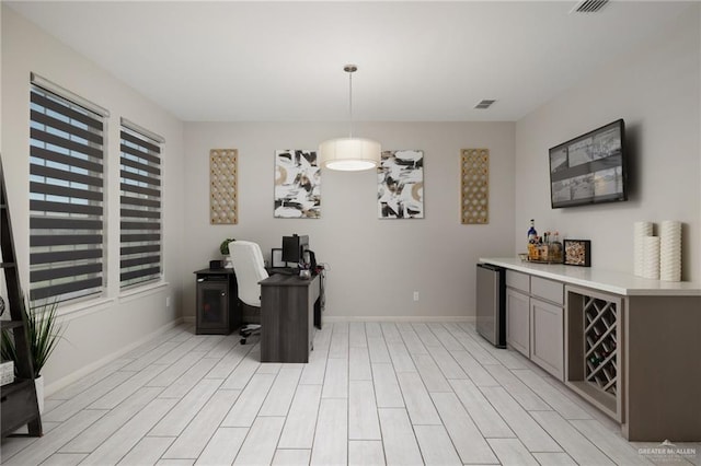 interior space with pendant lighting, stainless steel fridge, a wealth of natural light, and light hardwood / wood-style flooring