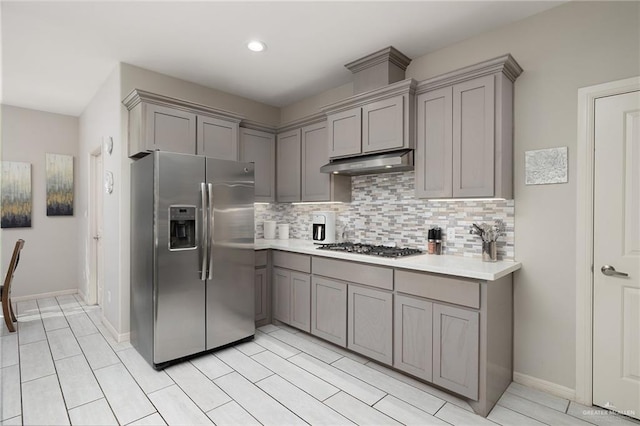 kitchen with gray cabinets, decorative backsplash, and stainless steel appliances