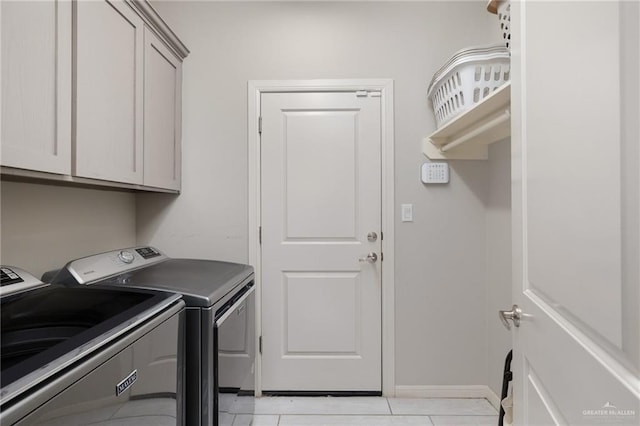 washroom featuring washer and clothes dryer, light tile patterned floors, and cabinets