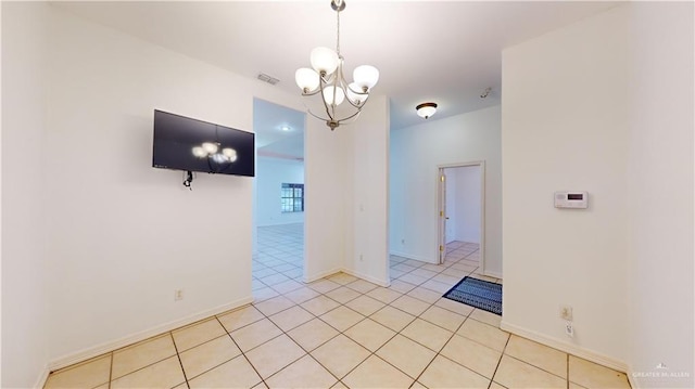 spare room featuring light tile patterned flooring and a chandelier