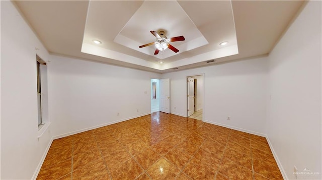 unfurnished room featuring a raised ceiling and ceiling fan