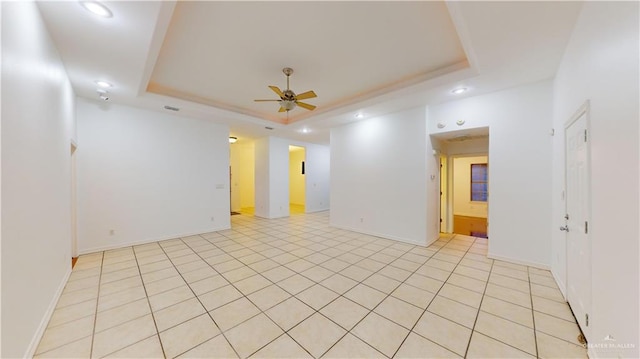 tiled spare room with a tray ceiling and ceiling fan