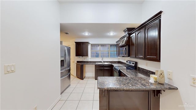 kitchen with dark brown cabinets, light tile patterned floors, kitchen peninsula, and appliances with stainless steel finishes