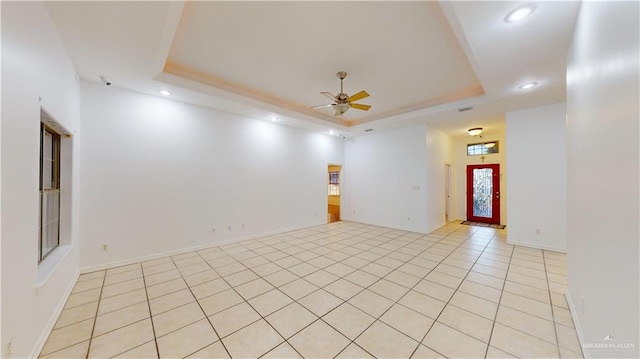 spare room with light tile patterned floors, a raised ceiling, and ceiling fan