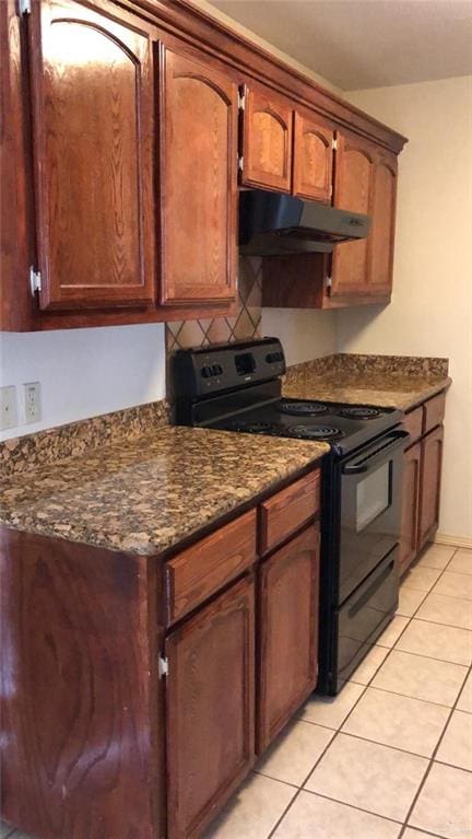 kitchen with under cabinet range hood, decorative backsplash, black range with electric cooktop, and light tile patterned flooring