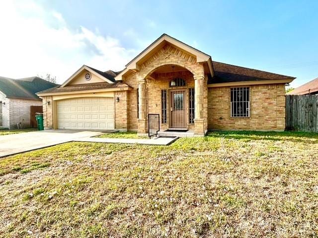 ranch-style home with brick siding, fence, a front yard, a garage, and driveway