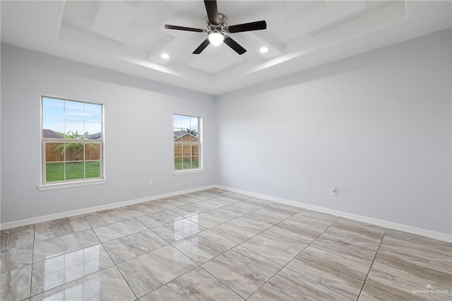 spare room featuring ceiling fan and a raised ceiling