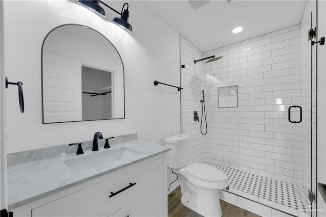 bathroom with vanity, wood-type flooring, a shower with door, and toilet