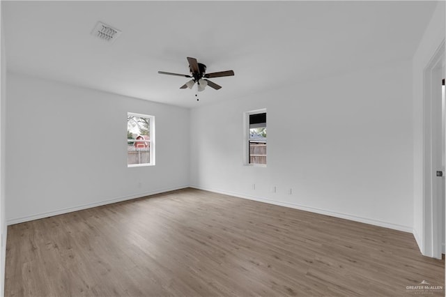 unfurnished room featuring plenty of natural light, ceiling fan, and light wood-type flooring