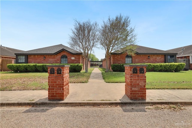 view of front of home featuring a front lawn, a shingled roof, fence, and brick siding