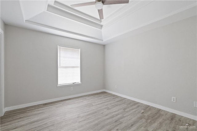 unfurnished room featuring baseboards, wood finished floors, a ceiling fan, and a raised ceiling