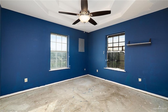 unfurnished room with ceiling fan, electric panel, a wealth of natural light, and a tray ceiling