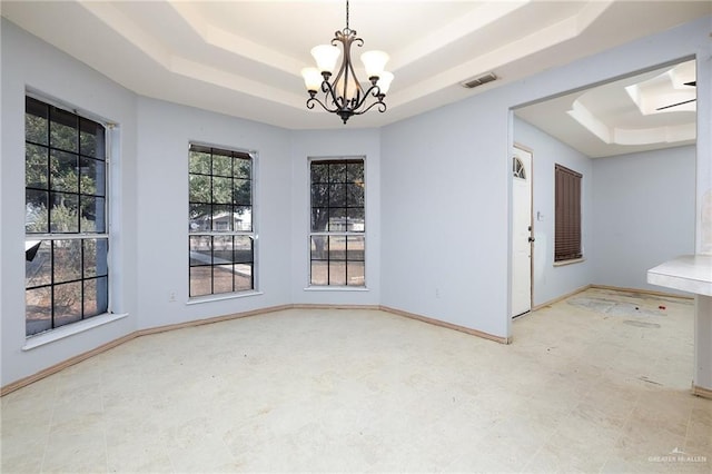 unfurnished dining area with a chandelier and a tray ceiling