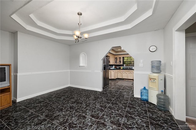 dining space with an inviting chandelier and a tray ceiling