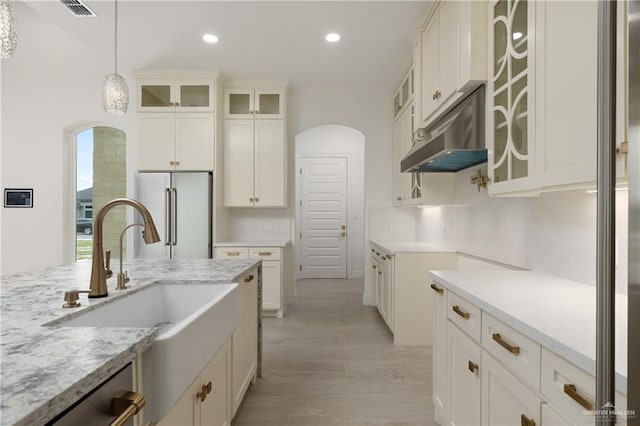 5407 Common Ln, Weslaco, TX 78596 - kitchen with high quality fridge, arched walkways, under cabinet range hood, a sink, and recessed lighting
