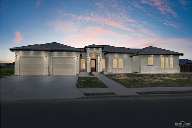 5407 Common Ln, Weslaco, TX 78596 - view of front of property featuring a garage, concrete driveway, stone siding, and stucco siding