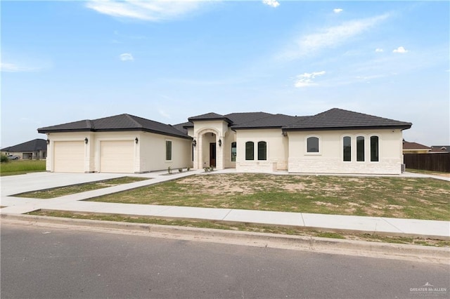 5407 Common Ln, Weslaco, TX 78596 - view of front of house featuring an attached garage, concrete driveway, stucco siding, and a front yard