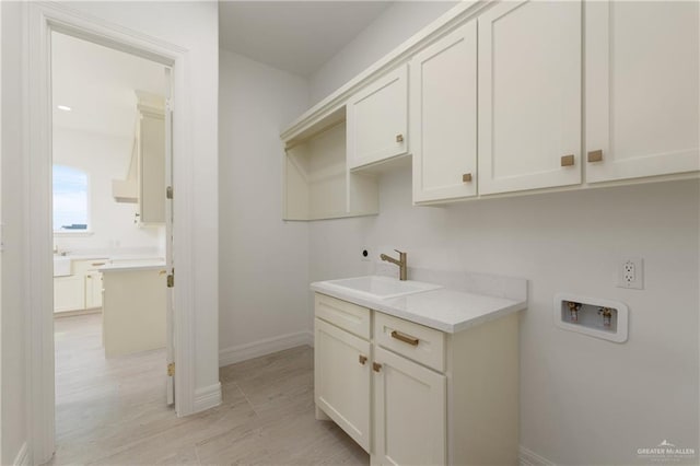 5407 Common Ln, Weslaco, TX 78596 - washroom featuring washer hookup, cabinet space, baseboards, and light wood-style flooring