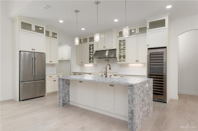 5407 Common Ln, Weslaco, TX 78596 - kitchen featuring high end refrigerator, beverage cooler, arched walkways, under cabinet range hood, and a sink