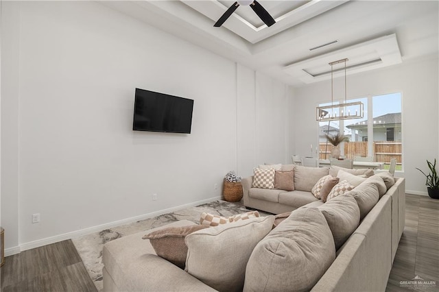 living room featuring a raised ceiling, ceiling fan, and wood-type flooring