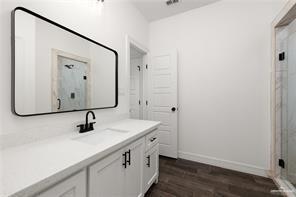 bathroom featuring wood finished floors, visible vents, vanity, baseboards, and a stall shower