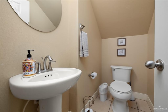 bathroom featuring tile patterned flooring, vaulted ceiling, sink, and toilet