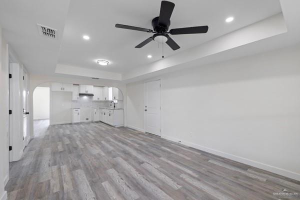 1311 Carlos Dr, Alamo, TX 78516 - unfurnished living room with a raised ceiling, arched walkways, light wood-style floors, and recessed lighting