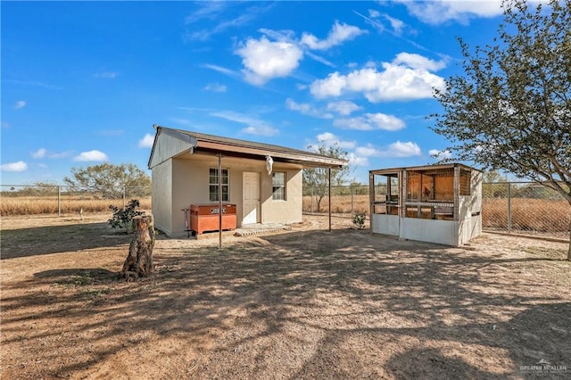 rear view of property with an outdoor structure and a rural view