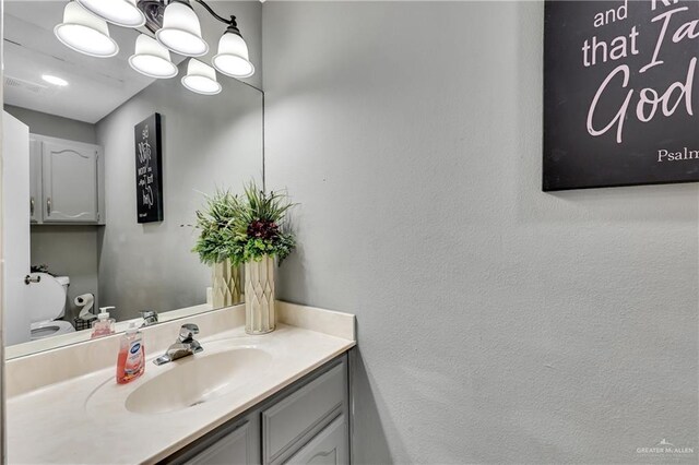 bathroom with vanity, toilet, and a notable chandelier