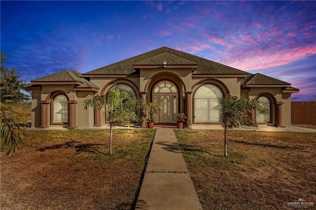 mediterranean / spanish home with a lawn and french doors