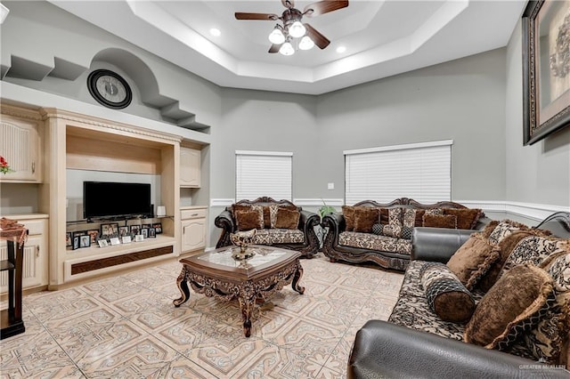 living room with a high ceiling, ceiling fan, and a tray ceiling