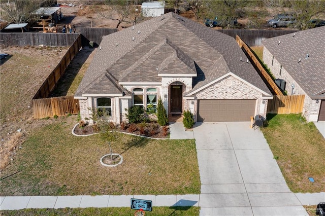 view of front facade featuring concrete driveway, an attached garage, fence, and a shingled roof