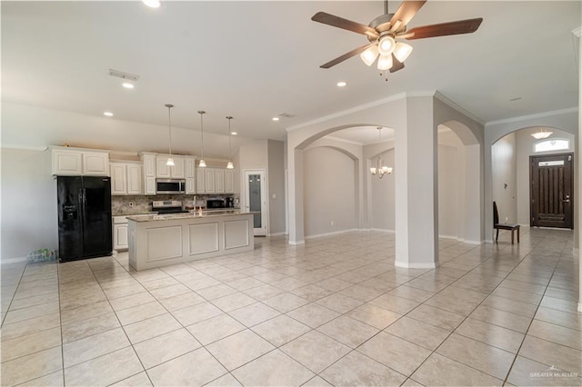 kitchen with backsplash, arched walkways, light tile patterned flooring, appliances with stainless steel finishes, and open floor plan