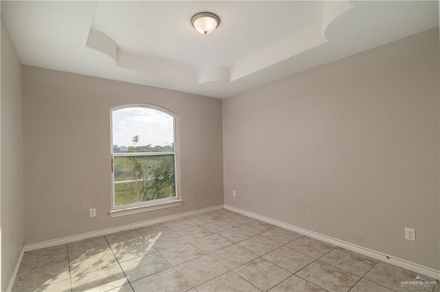 spare room with a raised ceiling and baseboards
