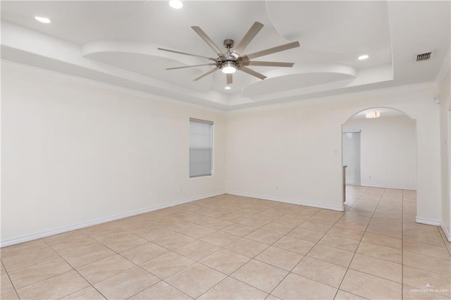 tiled empty room featuring a tray ceiling, ceiling fan, and ornamental molding