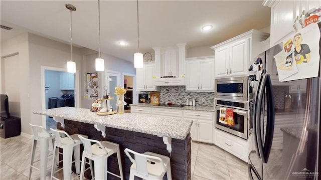 kitchen featuring independent washer and dryer, white cabinetry, hanging light fixtures, and appliances with stainless steel finishes