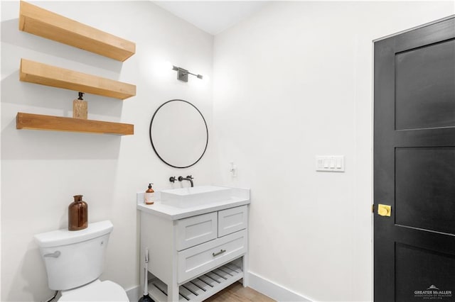 half bath featuring toilet, vanity, and baseboards