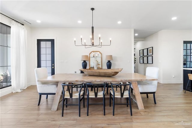 dining area with a notable chandelier, recessed lighting, light wood-type flooring, and baseboards