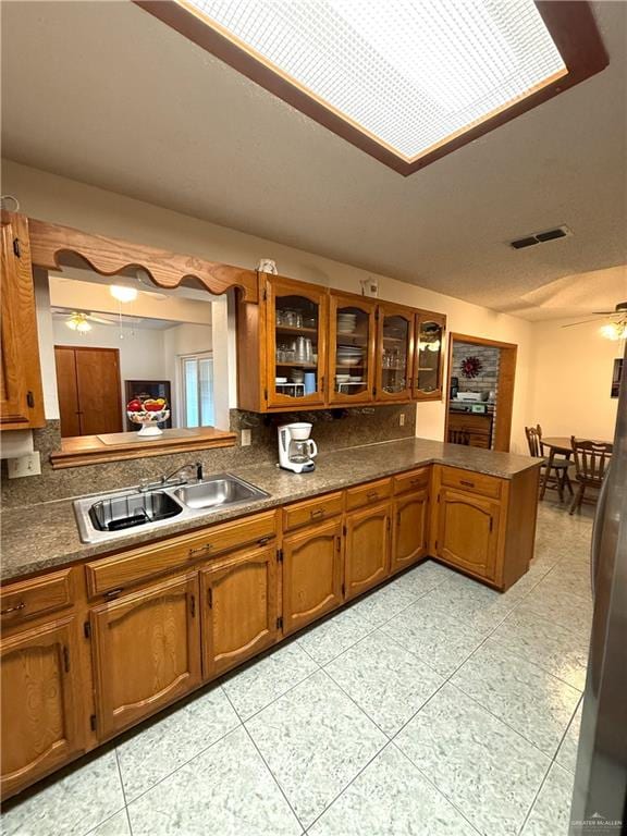 kitchen featuring ceiling fan, kitchen peninsula, sink, and light tile patterned floors